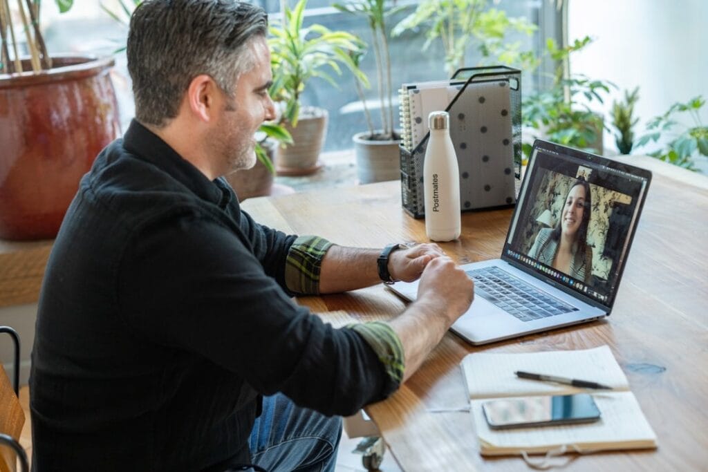 A man sitting at his desk using his computer for a video call. 