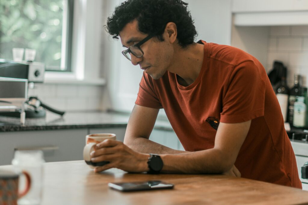 Person sitting at the kitchen counter anxiously staring into their coffee cup.