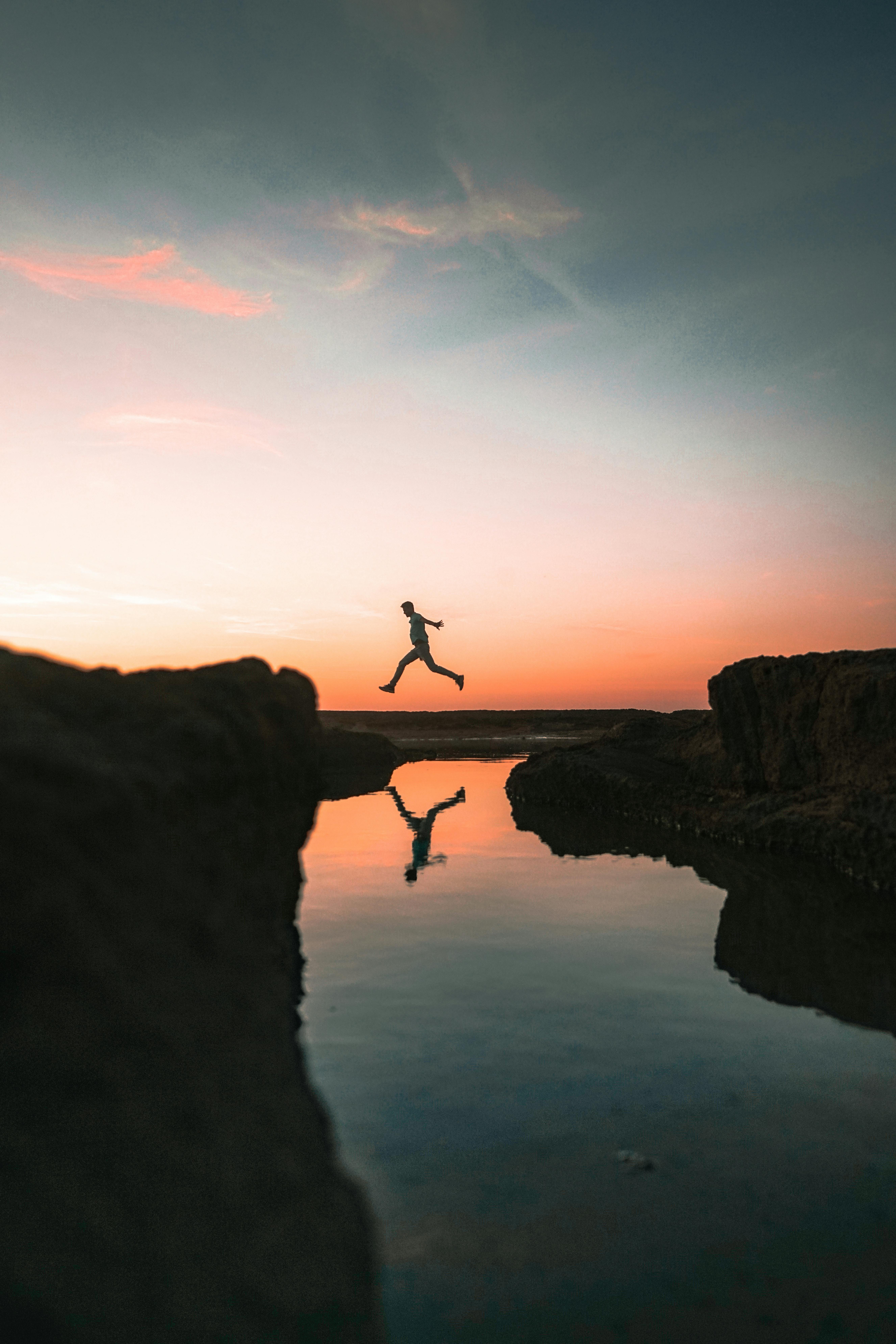Person trusting themselves as the leap across a stream. 